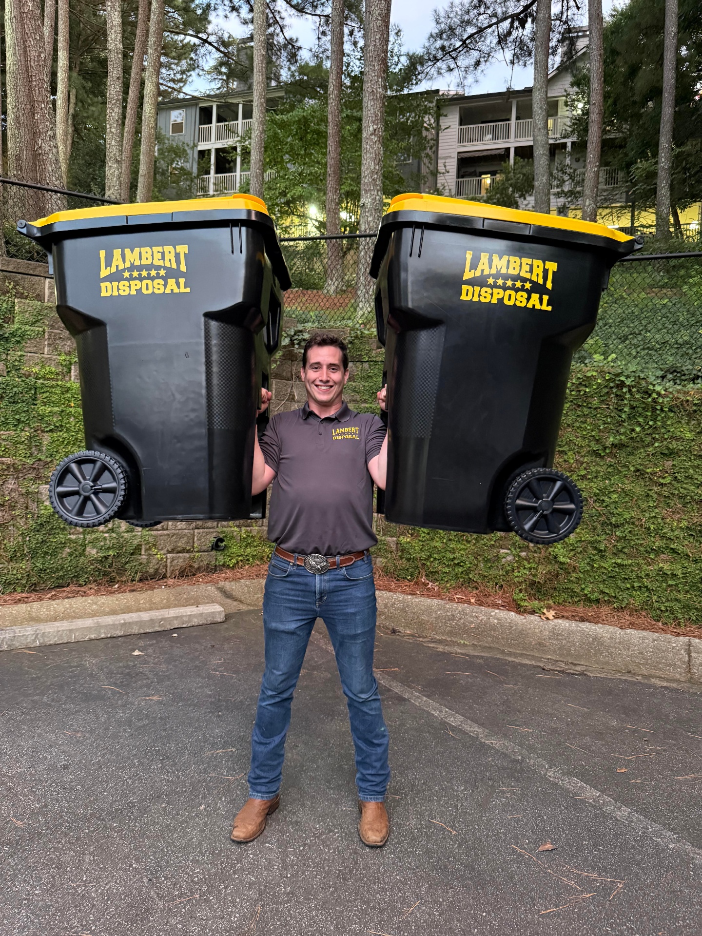 Joseph Lambert, owner of Lambert Disposal, holding two Lambert Disposal bins overhead